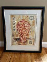 Full front view of a framed art print depicting a red Asian-style vase with calligraphy and paper textured background. The frame is black with gold trim and includes a white mat.