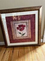 Frontal photo of square framed floral art print showing a red flower with multiple mat borders and wood brown stained frame.
