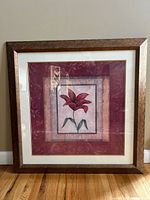 Front view of framed floral art print featuring red lily with double matting in white and gold within a medium brown wood frame.