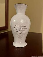 Front view of the white ceramic vase showing embossed decorative pattern and black inspirational inscription text on the body.