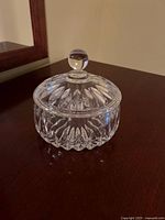 Closed view of the small round clear crystal candy dish with a faceted cut glass pattern and knob lid.