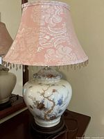 Full view of the porcelain table lamp with pink floral fabric shade and beaded fringe.