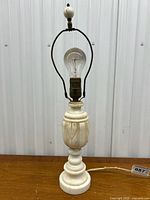 Full view of the alabaster table lamp showing the carved alabaster body, round base, metal harp and bulb.