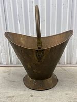 Front view of the antique brass coal bucket showing its large flared shape and circular base with moveable handle.