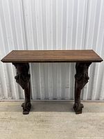 Front view of antique carved walnut side table showing solid top and detailed carved legs