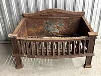 Front view of rusted antique cast iron fireplace log holder showing rectangular shape, slatted base, and sturdy legs.