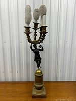 Full front view of the lamp showing figure, base, and candelabra arms