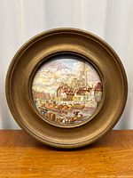 Frontal view of the Pratt Ware porcelain lid within a gilt frame, showing the historic harbor scene and overall item shape.