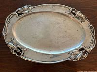 Full top view of oval silver tray showing the overall shape and decorative cut-out floral and leaf relief edge detailing.