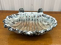 Top angle view of cast iron shell-shaped garden decor showing paint wear and mounting holes.