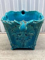 Front view of turquoise glazed jardiniere showing decorative foliage relief and scalloped rim.