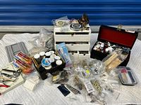 Overview of entire lot showing drawers, supply containers, tools, and jewelry making components spread out on white cloth