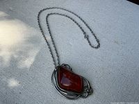Necklace laid flat showing the full length of the chain and pendant on fabric background.