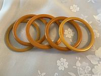 Six round butterscotch-colored Bakelite bangles arranged flat on floral fabric background