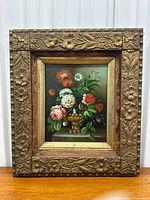 Full view of the framed floral oil painting showing intricate carved gilt floral frame and velvet matting.