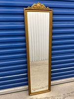 Full view of the full length mirror showing entire frame and reflective surface standing against blue storage unit door.