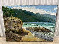 Full view of the oil painting showing the beach scene with rocks, ocean waves, mountains, and sky.