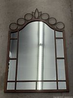 Full view of the entire wrought iron framed mirror showing windowpane mirror design and decorative top.