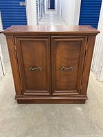 Front full view of vintage wooden cabinet nightstand with French-style double doors and brass handles.