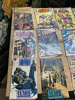 Top view showing eight bagged comics including GI Joe, Avengers Annual, Adventure Presents Warrior, New Mutants, two Batman Legends of the Dark Knight Venom issues, Justice and New Wave