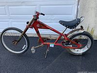 Side view of red Schwinn OCC Sting-Ray chopper bicycle showing full frame, wheels, seat, and overall condition