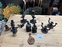 Group shot of all cast iron candle holders, two miniature stoves and wall plaque