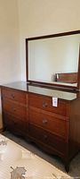 Front view of dresser with attached mirror and glass top showing overall condition and design.