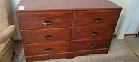 Front view of 6 drawer wooden dresser with vintage drawer pulls, showing overall condition and finish.