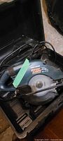 Black & Decker circular saw inside black carrying case with power cord coiled on top.