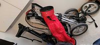 View of folded golf push cart with attached red golf bag