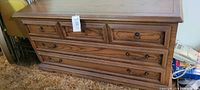 Front view of large wooden chest with multiple drawers and metal pulls, showing condition and style.