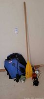 Full view of lifejacket, paddle leaning against wall, and oil cans on floor