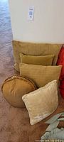 Includes five pillows showing various shapes and sizes in olive green and tan tones.