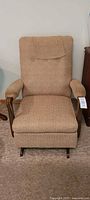 Front view of vintage rocker chair showing beige fabric, padded armrests, and wooden rocker base.