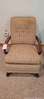 Front view of the vintage taupe patterned upholstered chair showing unique curved wood armrests and cushioned seat and back.