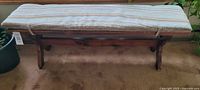 Wood bench with vintage cushion from the side view showing full length and cushion details