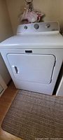 Full view of the white Maytag dryer showing front door and control panel in laundry room environment.