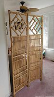 Full view of the 3-panel bamboo folding room divider standing upright in a room near a window.