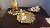 Anniversary clock, brass decorative bowls, and mixed shell bowl arranged on dark table