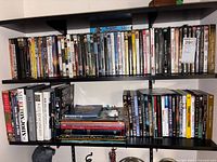 Full shelving view showing a large number of assorted DVDs and some books on two shelves.