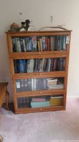 Front view of oak barrister bookcase showing all four glass-front sections filled with books
