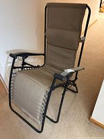 Front angle view of beige zero gravity lounge chair showing padded headrest, armrests and fabric seat with bungee lacing on sides, black metal frame visible.