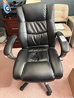 Front view of black faux leather office chair showing padded cushioned seat and armrests.