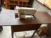 Brother electric sewing machine mounted on wooden table with foldable sections extended.