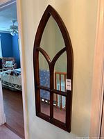 Full view of the Gothic arch windowpane wall mirror against a wall, highlighting its shape and multiple windowpane divisions.