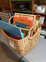 Photo of woven basket filled with children's books, showing basket texture and some book spines.