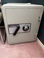 Front angle view of beige steel safe showing combination dial and handle, minor surface wear visible.