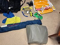 Wide view of the set showing the navy Tommy Bahama bag, grey soft bag, blue mask and snorkel, yellow mask and snorkel, gloves, and orange folding chair.