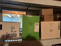 Boxes of wine glasses including Sociable and Variations brands arranged in basement storage area