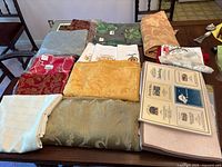 Photo of an assortment of folded table linens spread over a table including placemats, napkins, and tablecloths in various colors and patterns